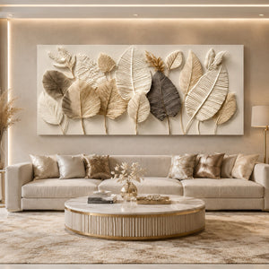 A large rectangular wall art piece featuring layered 2D leaf designs in beige, cream, and gray tones, displayed above a modern beige sofa in a styled living room.